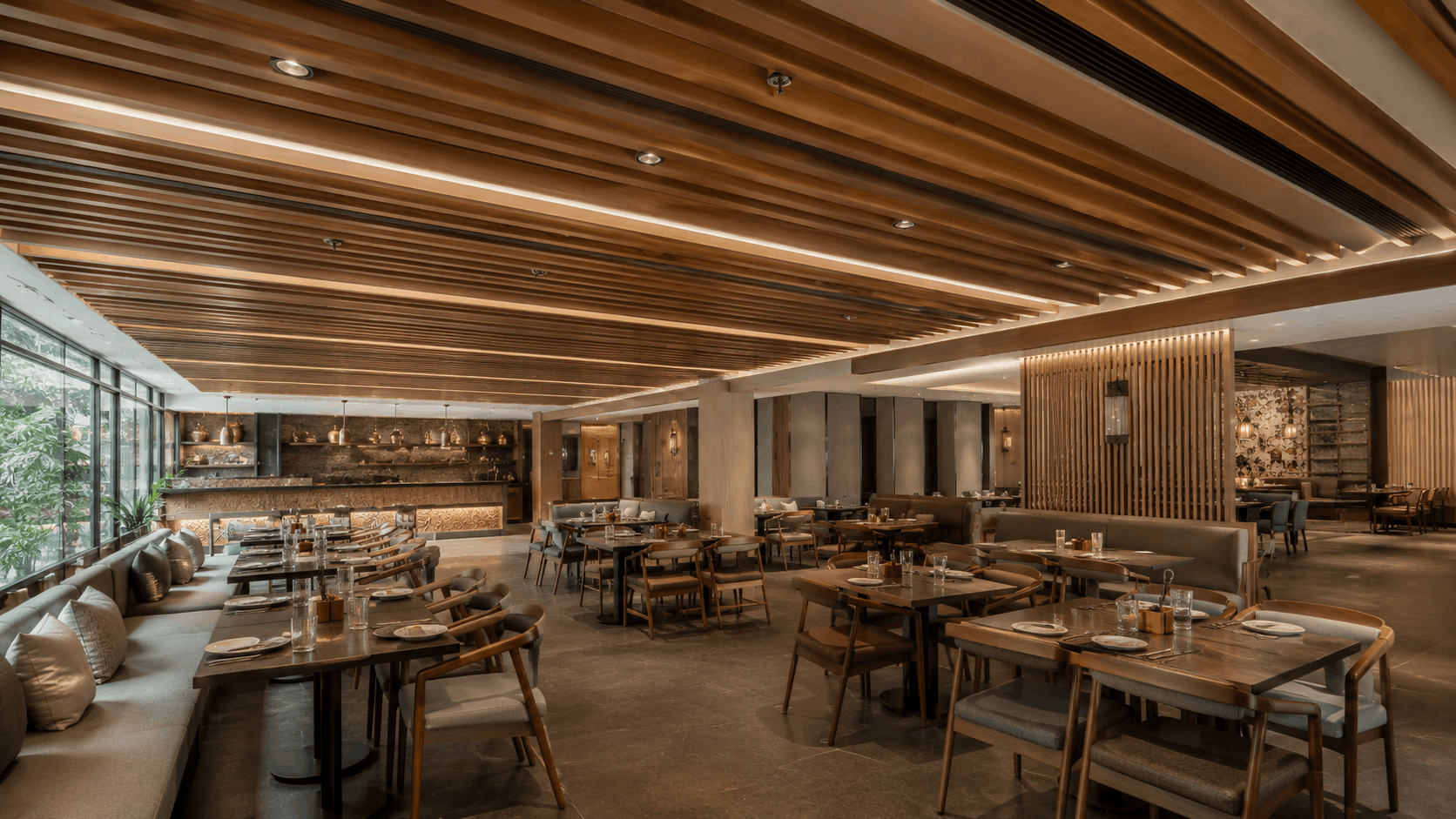 Warm wooden slat ceiling with integrated cove lighting above a restaurant dining and lounge area